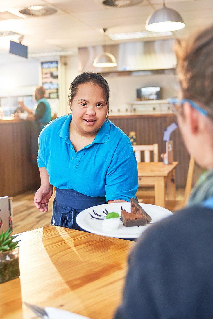 Young server with Down Syndrome serving dessert in cafe