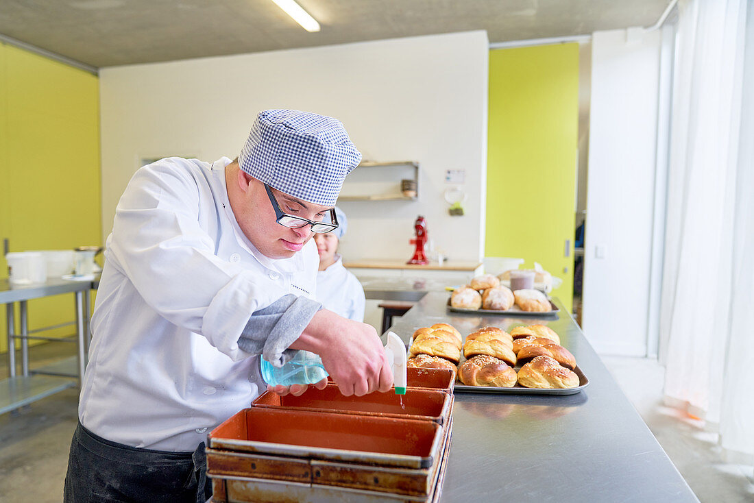 Focused man with Down Syndrome baking bread in kitchen