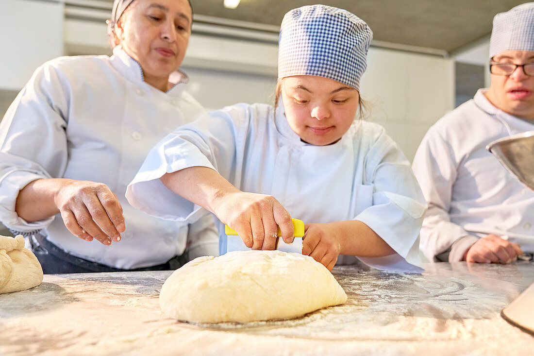 Woman with Down Syndrome cutting dough in baking class