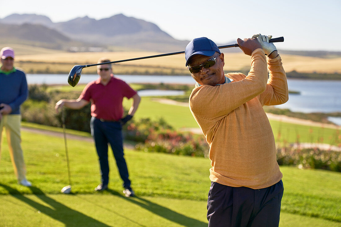 Mature male golfer teeing off at sunny box