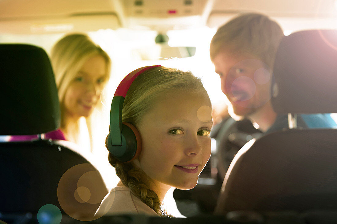 Portrait girl with headphones riding in back seat of car