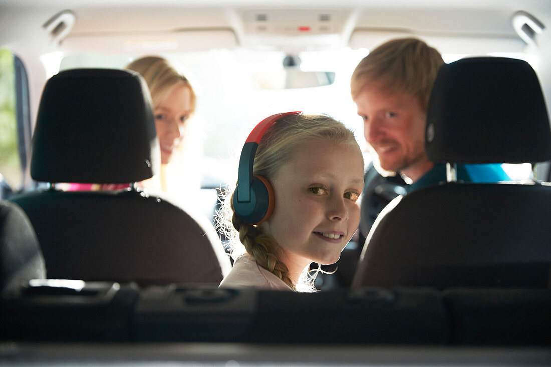 Portrait girl with headphones riding in back seat of car