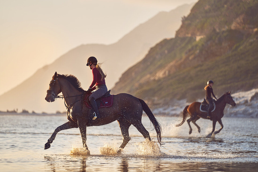 Young women horseback riding in ocean surf