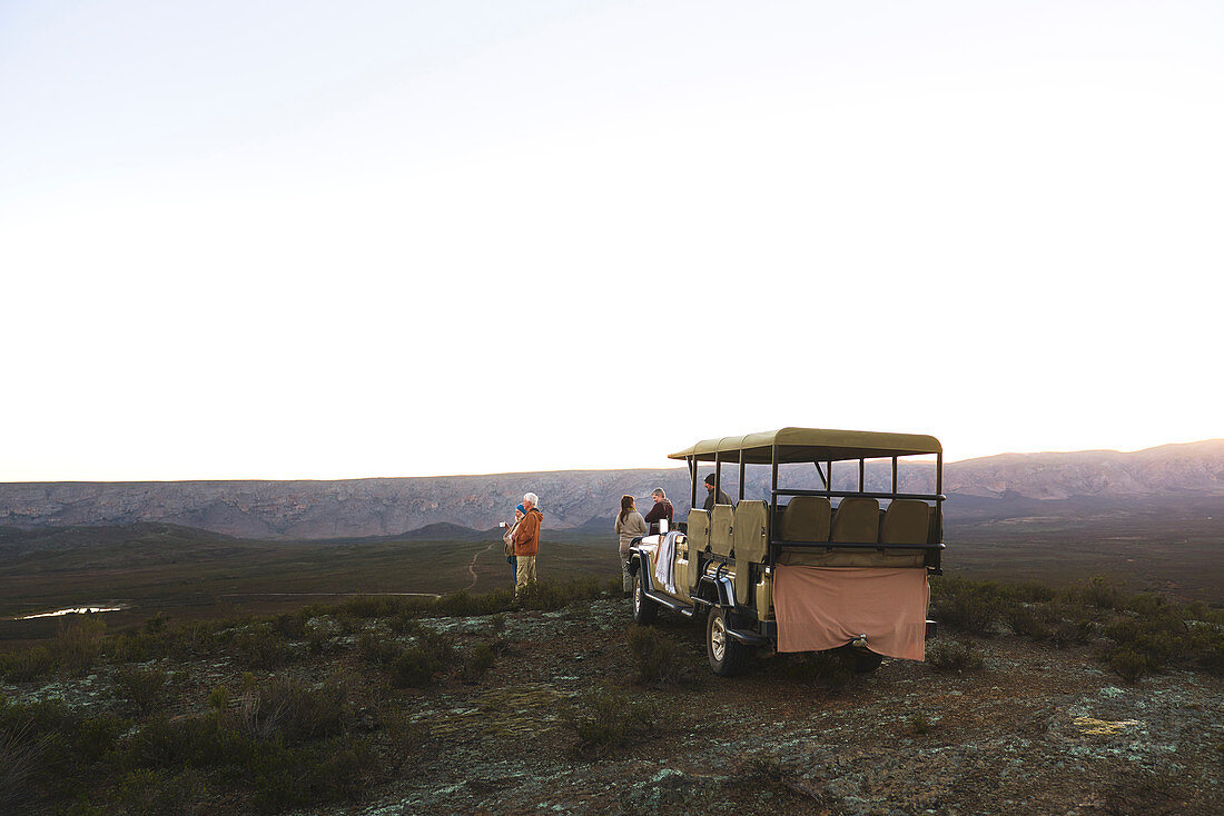 Group and off-road vehicle on remote hill at sunrise