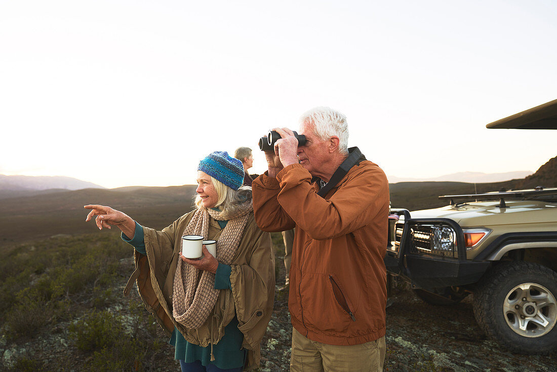 Senior couple with binoculars and tea on safari