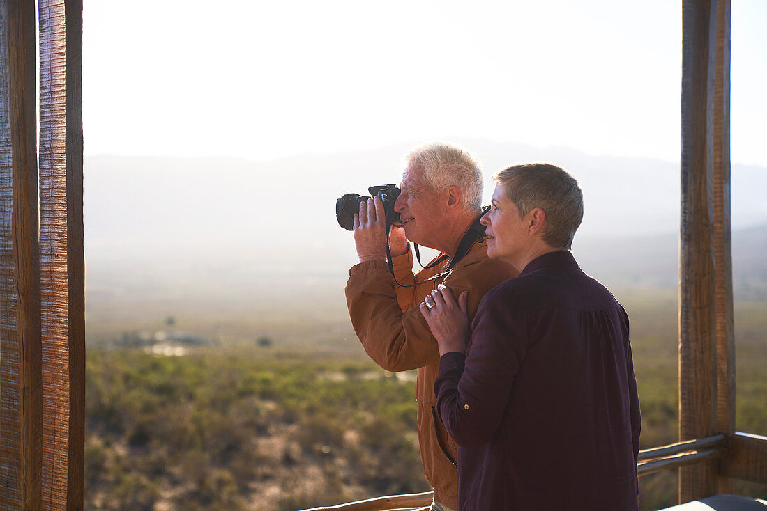 Senior couple with camera on sunny safari balcony