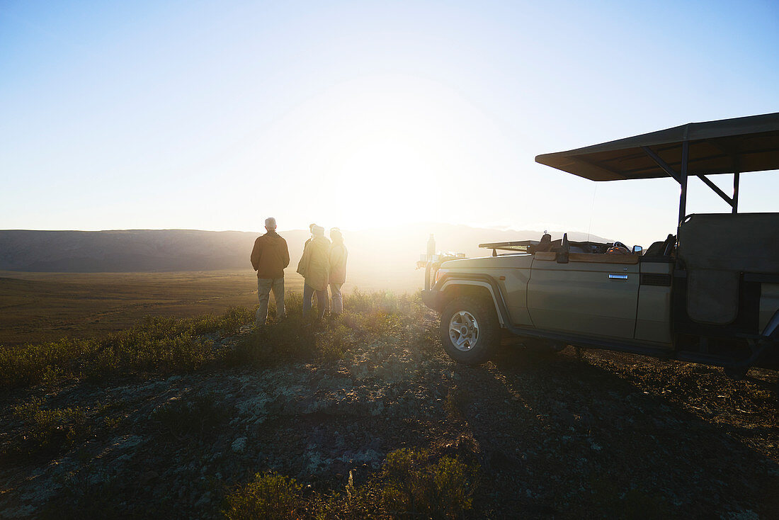 Group and off-road vehicle on hill at sunrise South Africa