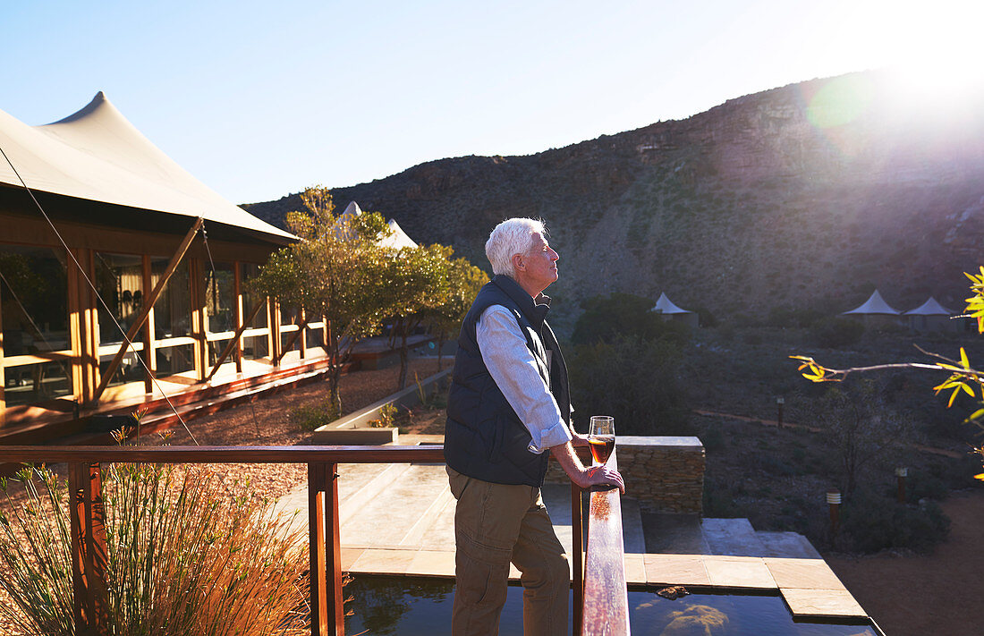 Serene senior man relaxing on sunny safari lodge balcony
