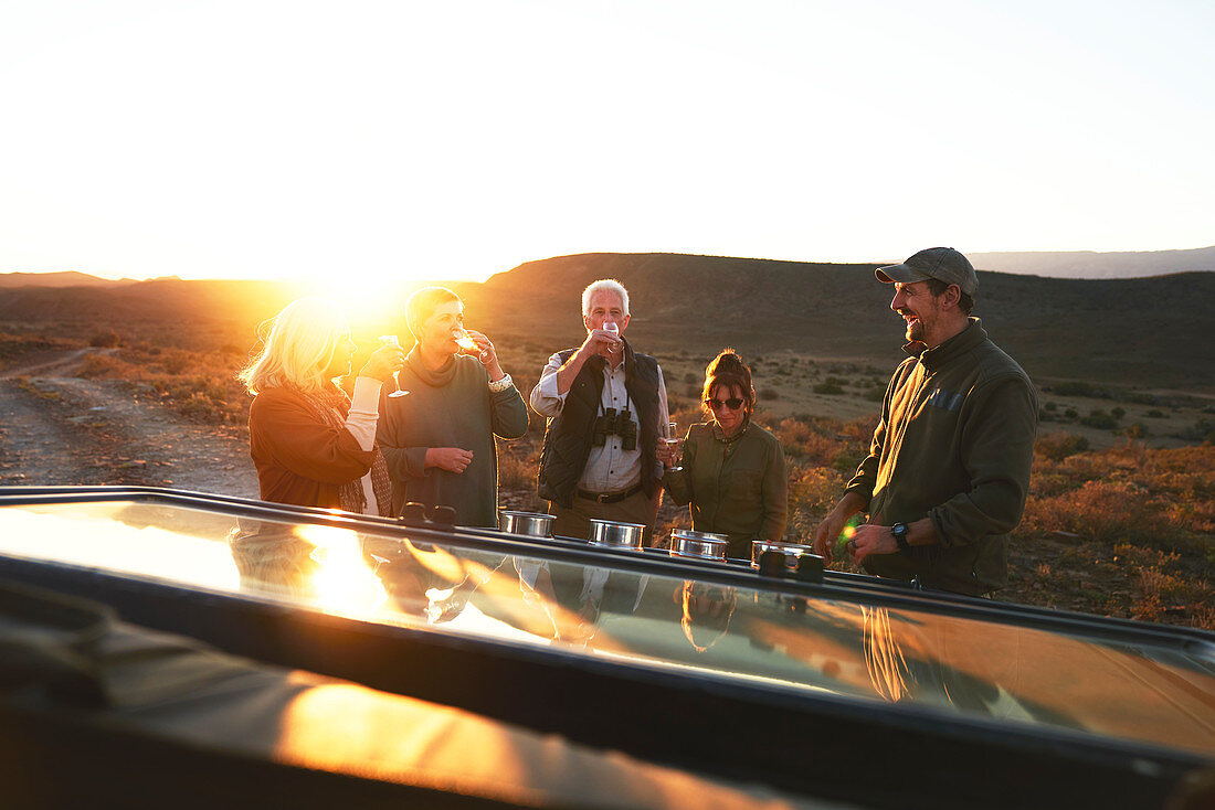 Safari tour group drinking champagne at sunset