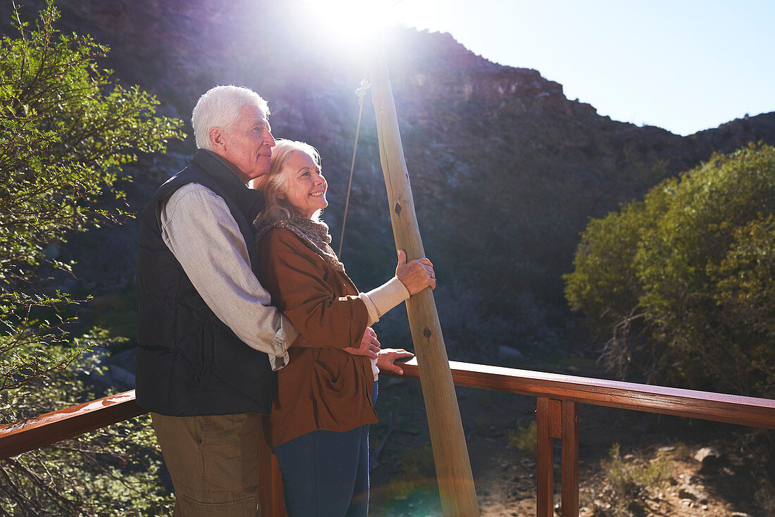 Happy senior couple relaxing on sunny balcony