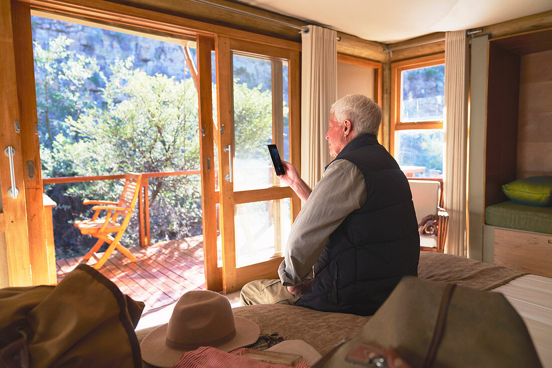 Senior man using smart phone on hotel bed