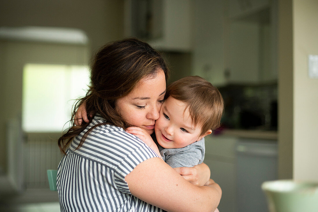 Affectionate mother hugging toddler daughter