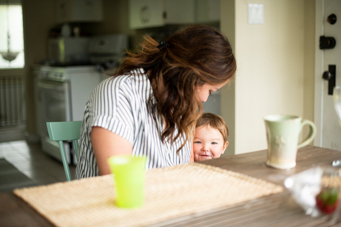 Mother and cute toddler daughter at kitchen table