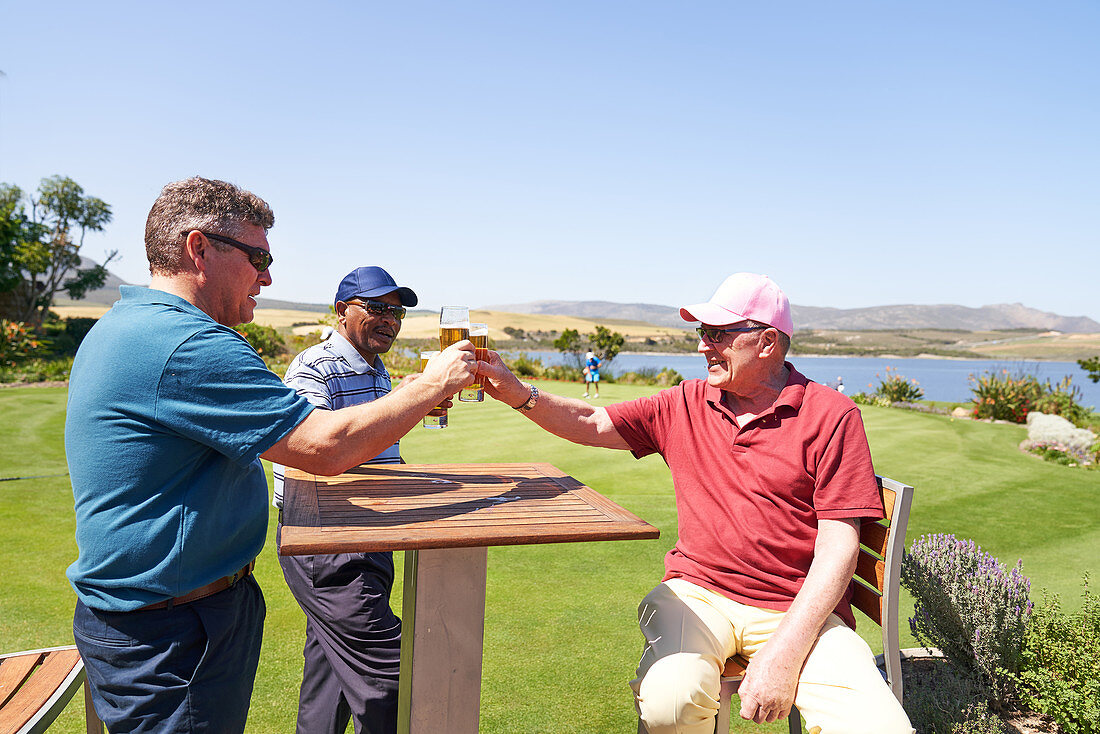 Mature golfers drinking beer on sunny golf clubhouse patio