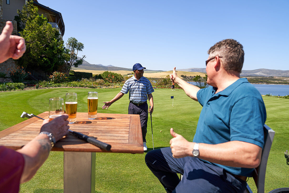 Male golfers drinking beer cheering friend