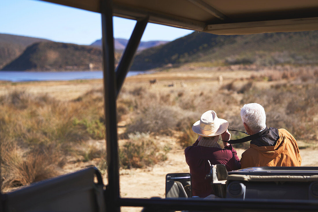 Senior couple on safari looking at view outside vehicle