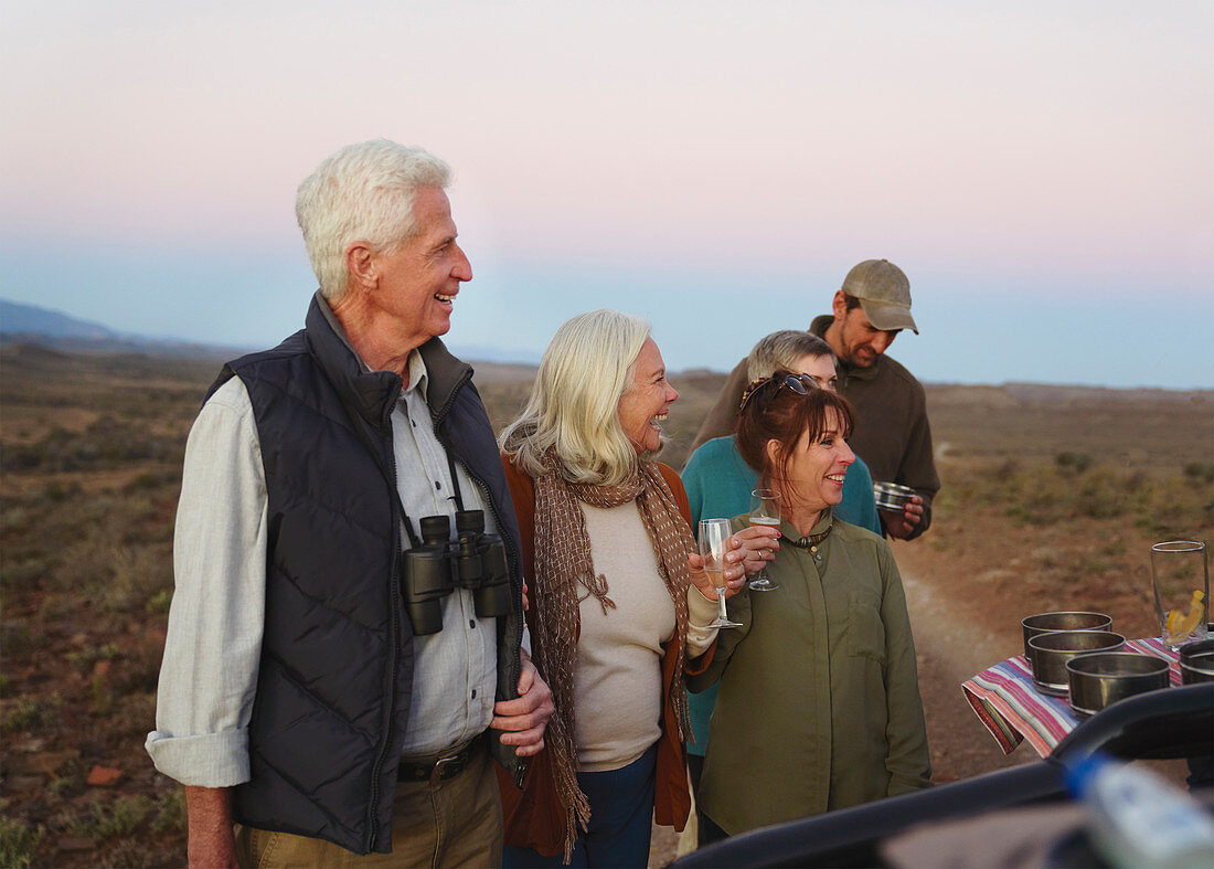 Happy senior couple on safari drinking champagne