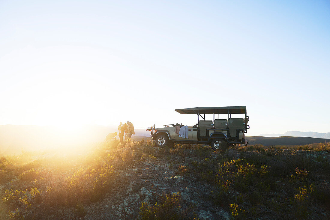Group outside off-road vehicle on tranquil hill at sunrise