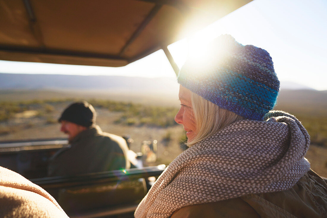 Happy senior woman riding in sunny safari off-road vehicle