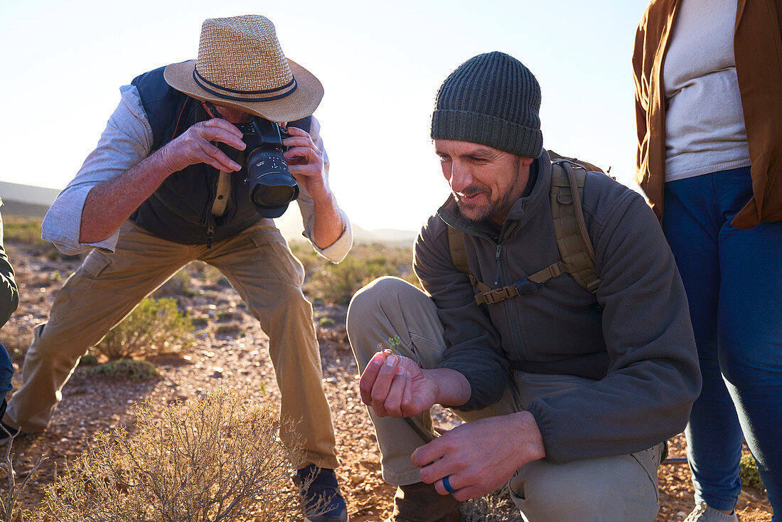 Safari tour guide explaining plants to tourist with camera
