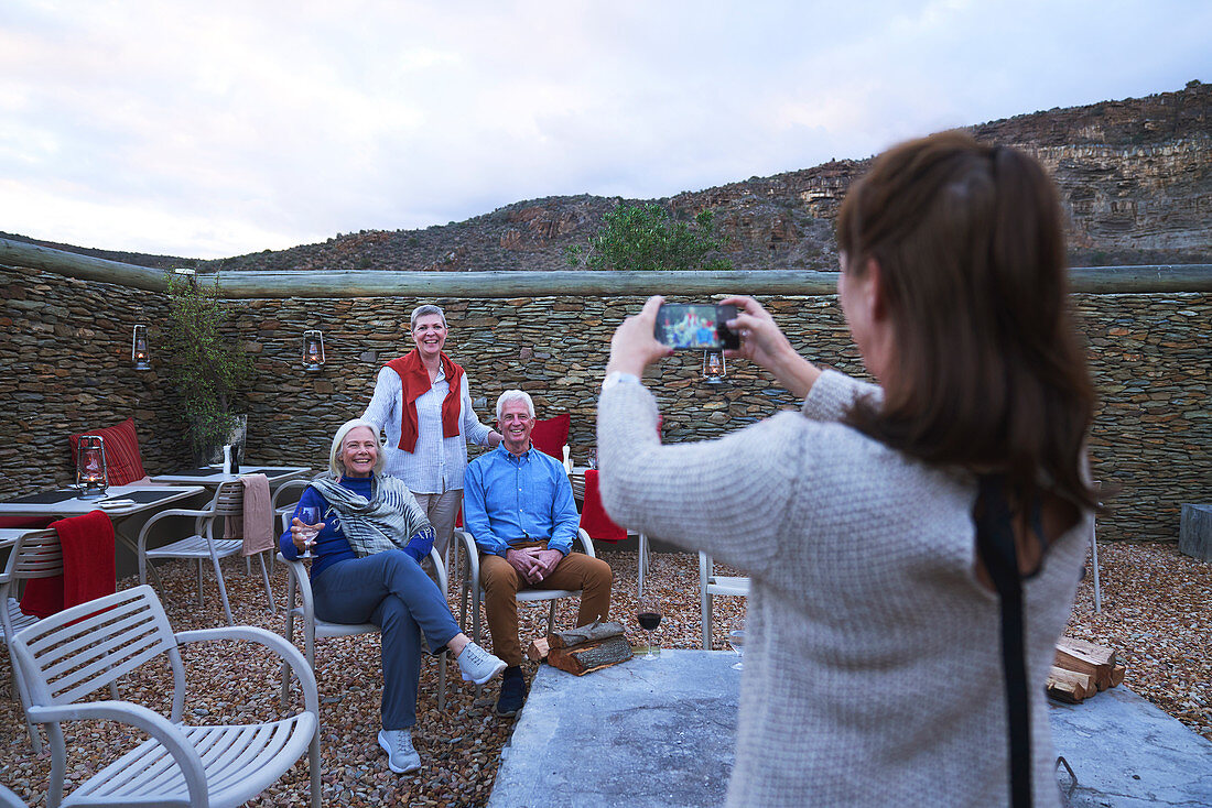 Woman with camera phone photographing friends on patio