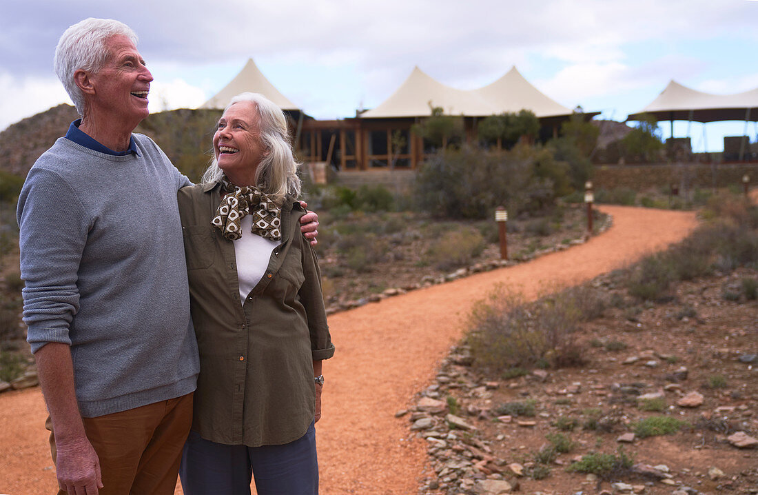 Happy senior couple on footpath outside safari lodge
