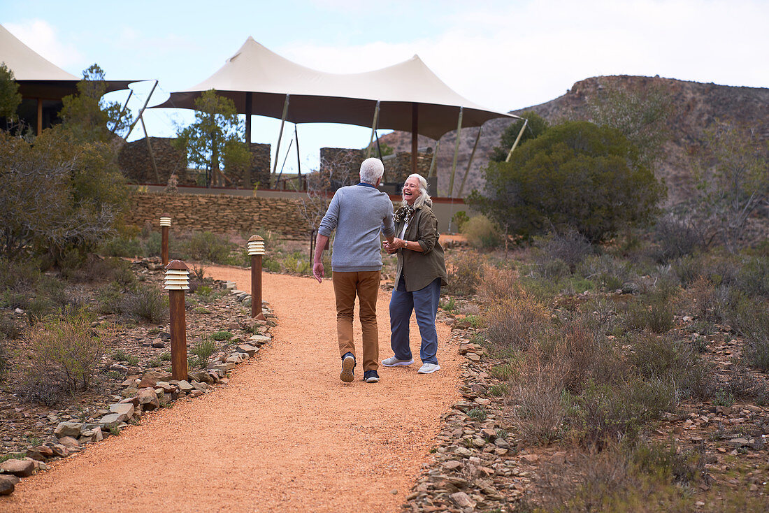 Senior couple walking on footpath outside safari lodge