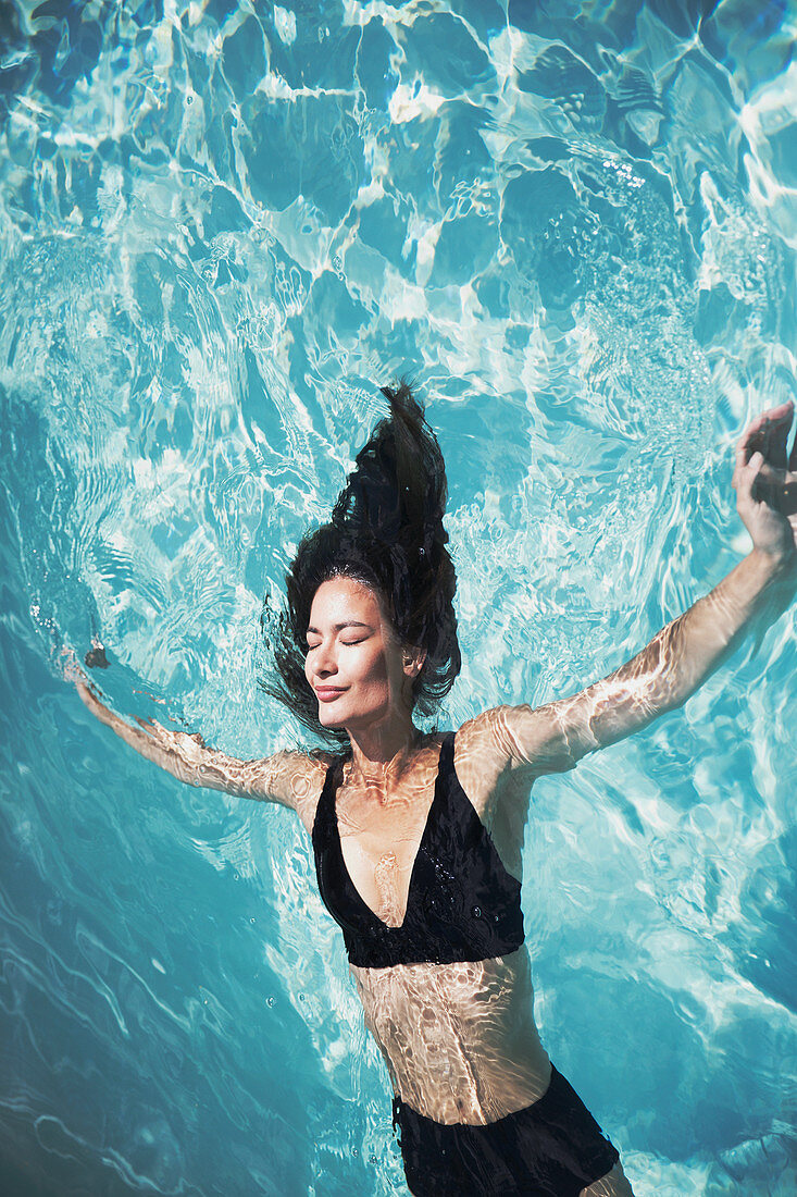 Woman floating in summer swimming pool
