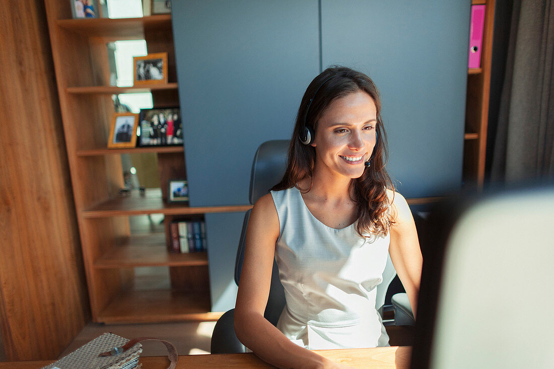 Smiling businesswoman with headset working in home office