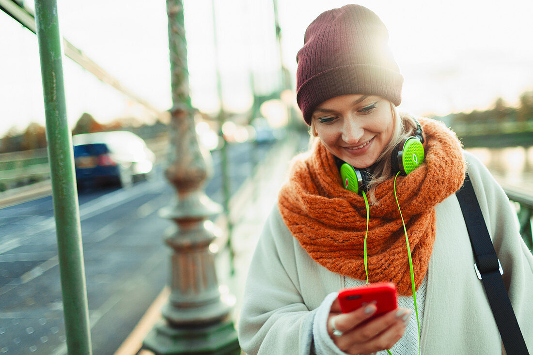 Woman in stocking cap and scarf texting with smart phone