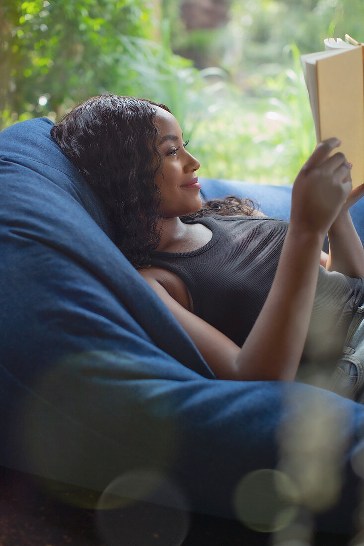 Serene woman relaxing reading book in beanbag chair