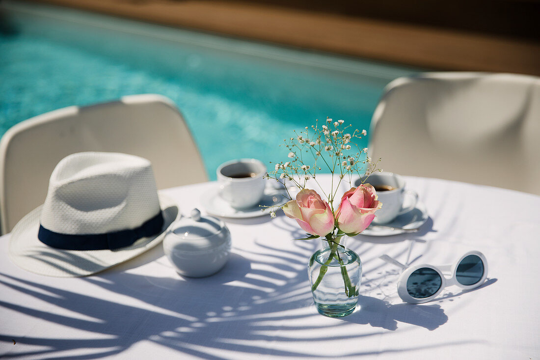 Roses and coffee on poolside patio table