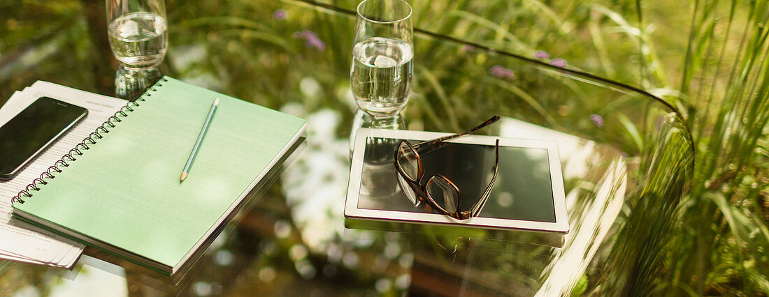 Digital tablet and eyeglasses on glass table