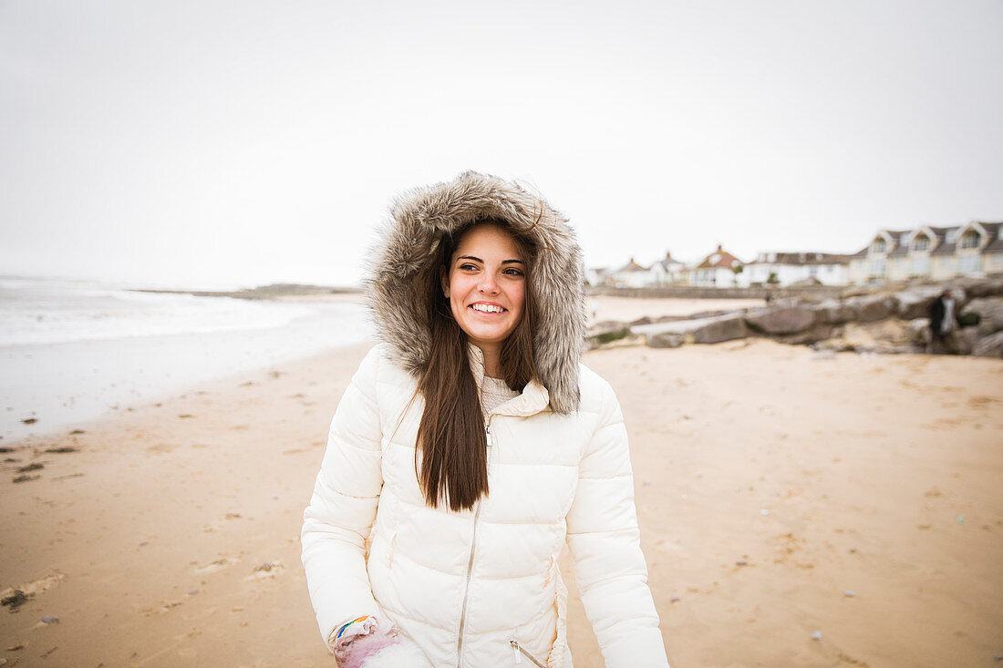 Carefree teenage girl in fur jacket on ocean beach