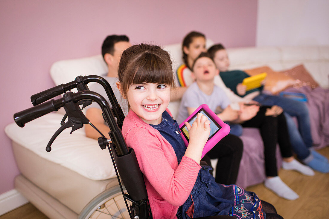 Happy girl in wheelchair using digital tablet