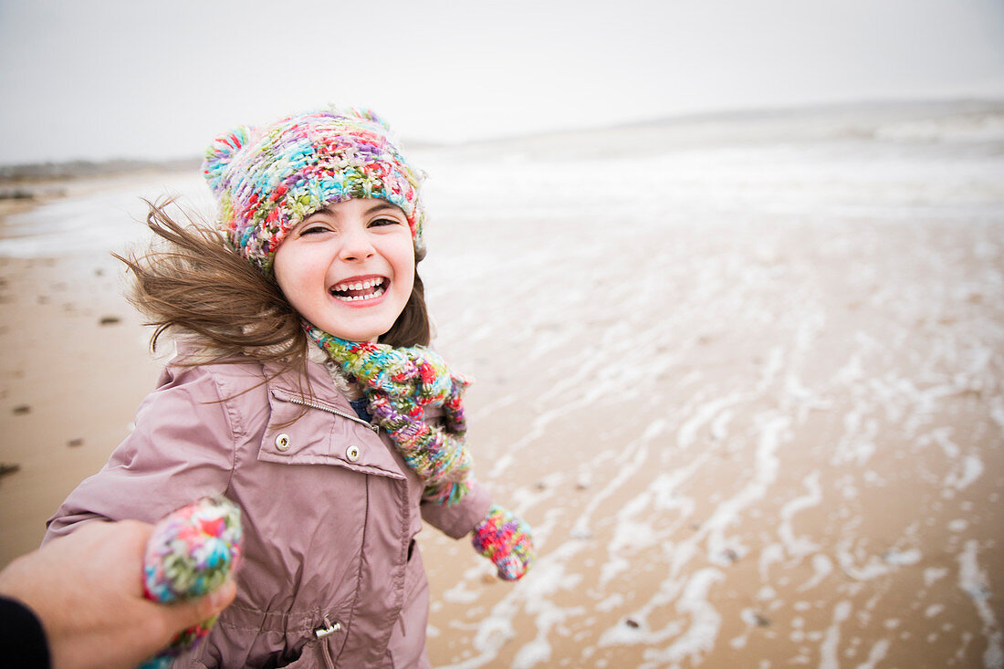 Portrait happy carefree girl running on winter beach