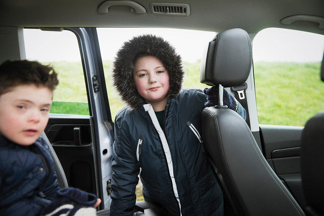 Portrait boy in fur hooded jacket in back seat of van