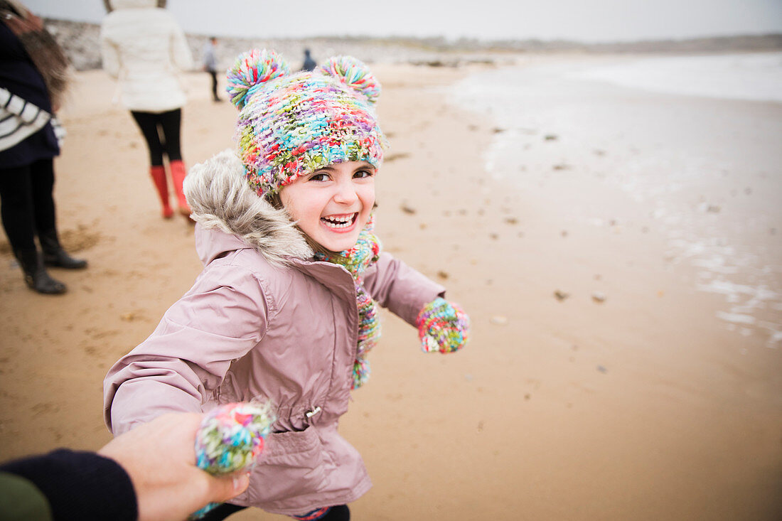 Carefree girl in warm clothing running on winter beach