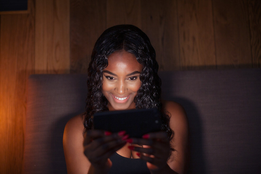 Woman using smart phone in dark bedroom