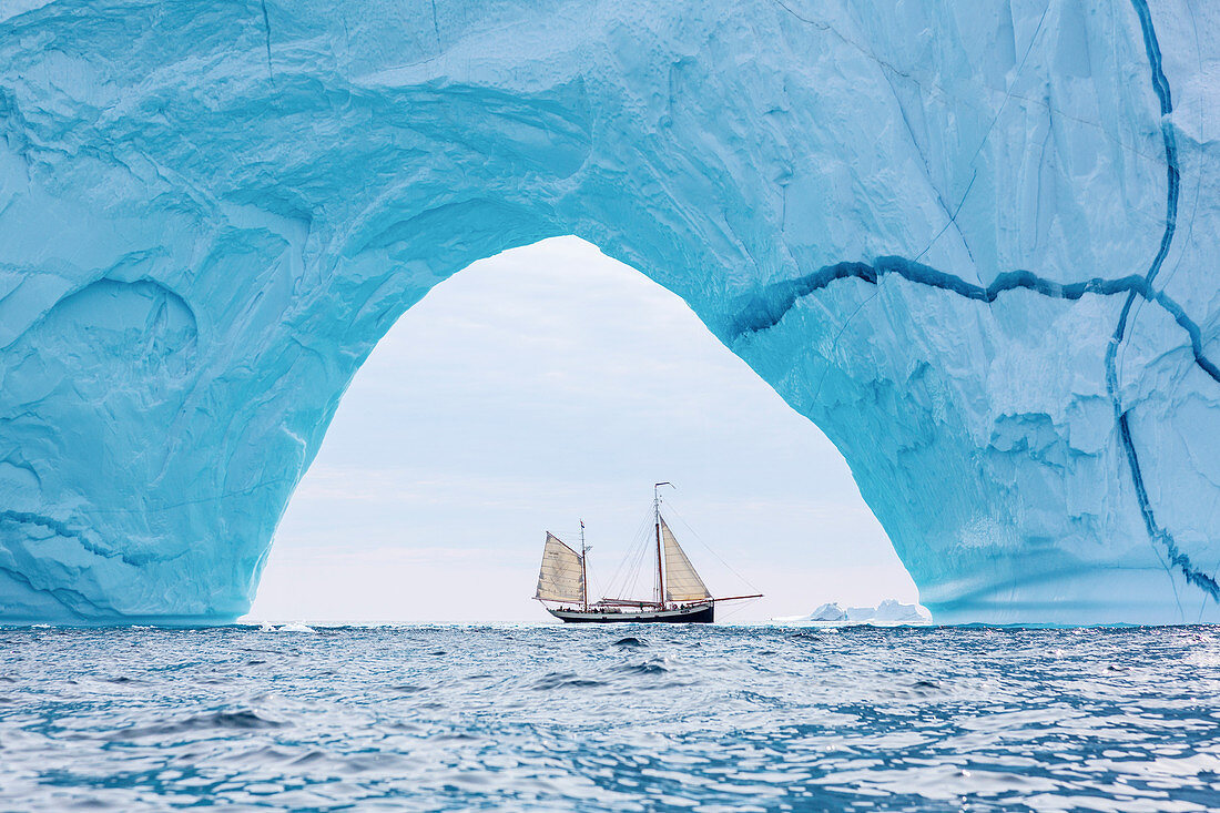 Ship sailing through majestic iceberg arch Greenland
