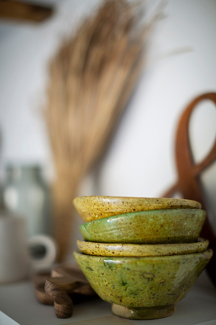Stacked green ceramic bowls on shelf