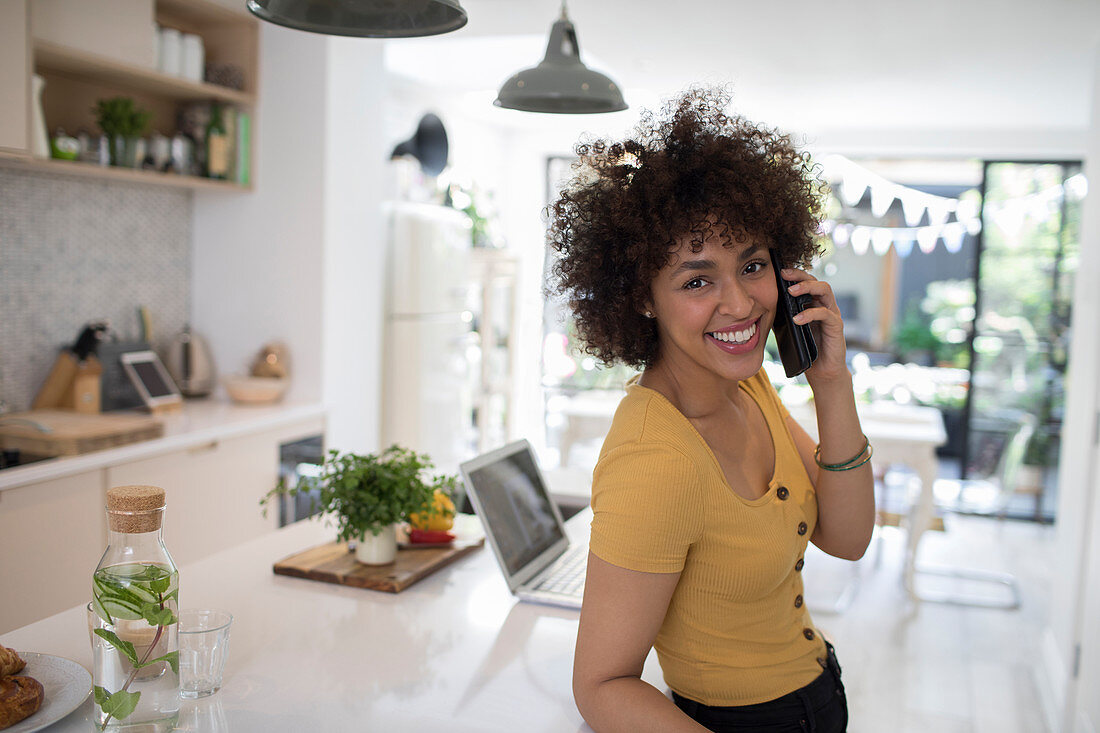 Woman talking on smart phone in kitchen