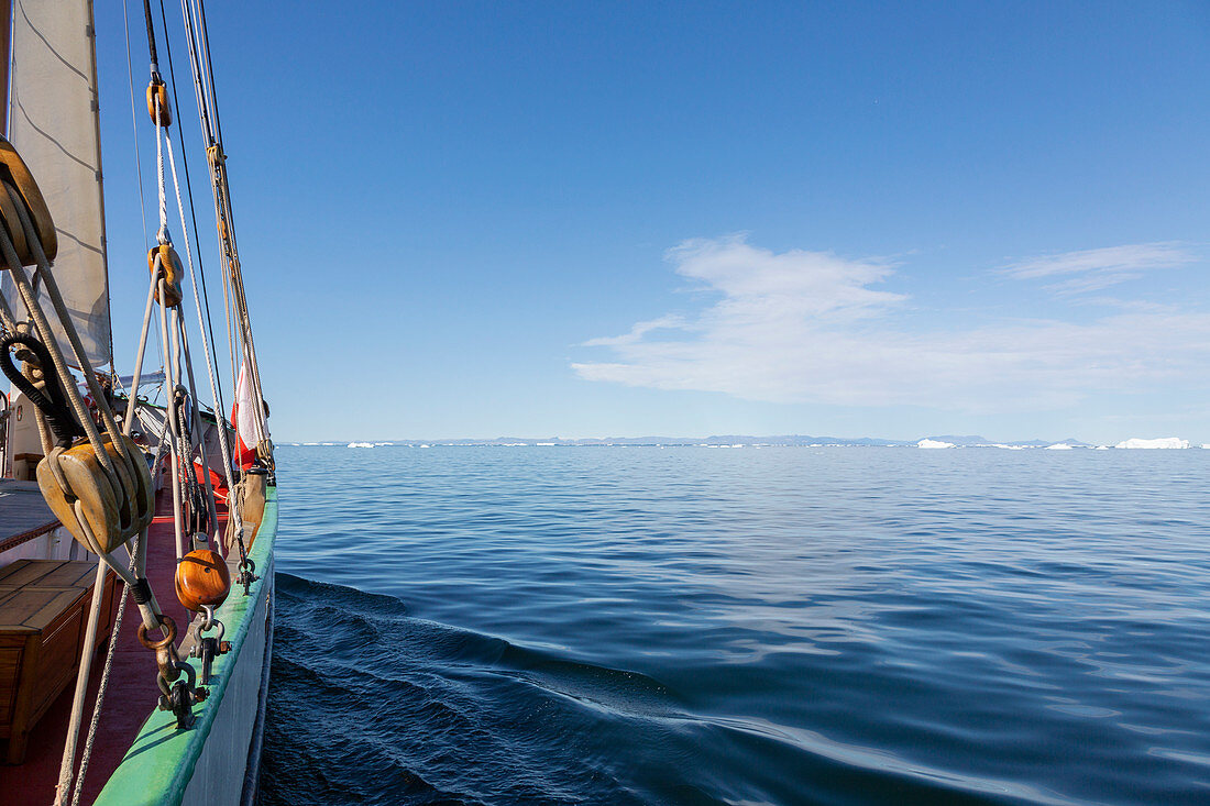 Ship sailing toward icebergs on tranquil blue