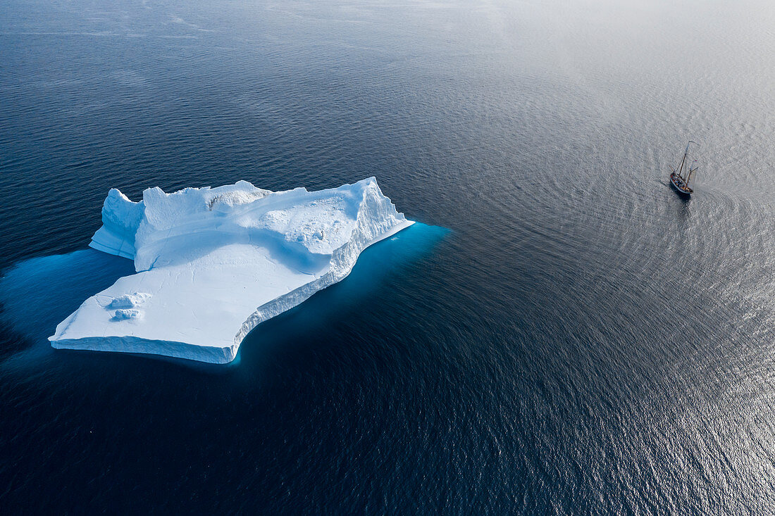 Ship sailing past majestic iceberg formation on blue