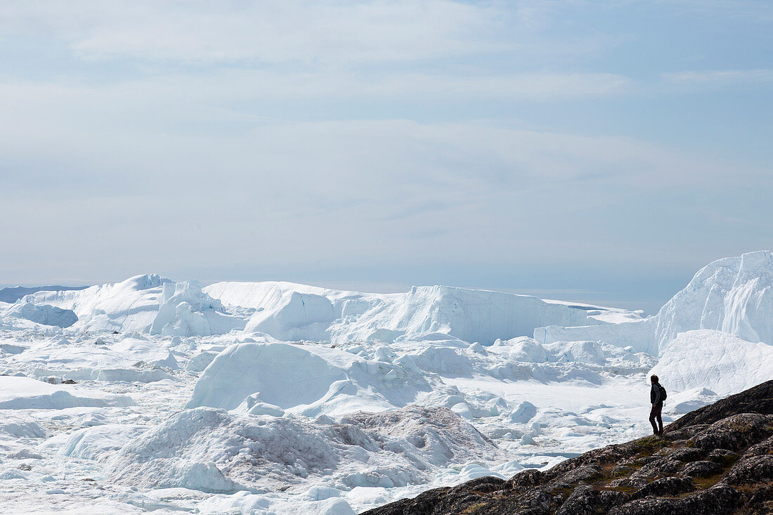 Man standing on cliff overlooking glacial ice melt