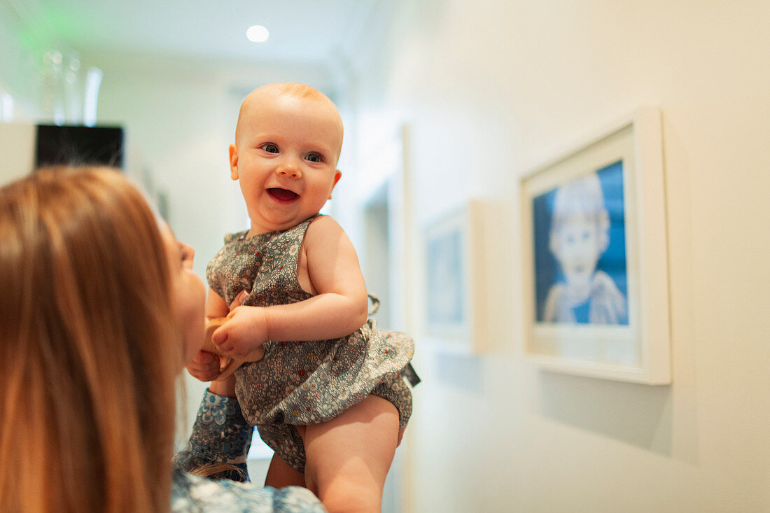 Mother holding happy cute baby girl in corridor