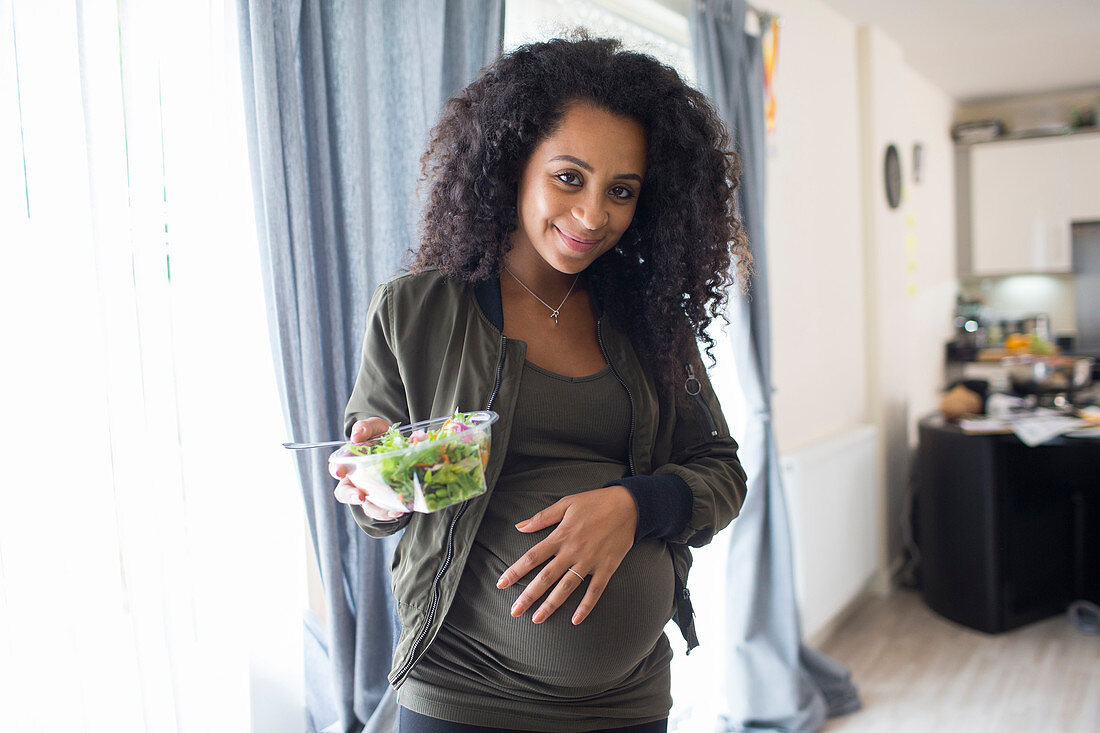Portrait happy pregnant woman eating salad