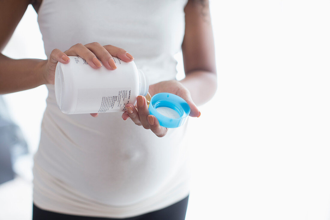 Young pregnant woman taking prenatal vitamins