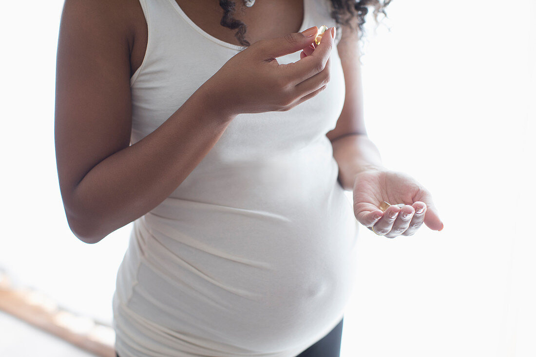 Close up pregnant woman taking prenatal vitamins
