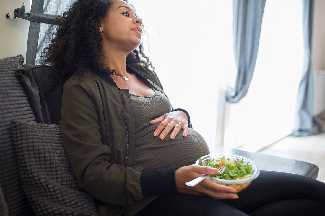 Tired pregnant woman eating salad